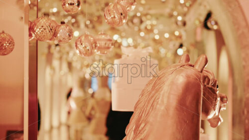 Video - Elegant close-up of a decorative horse statue displayed inside a warmly lit hallway filled with golden holiday lights and ornaments