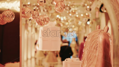 Video - Golden Christmas baubles hanging in a softly illuminated indoor corridor, creating a warm and magical holiday ambiance