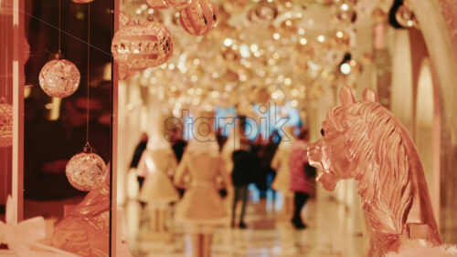 Video - Golden Christmas baubles hanging in a softly illuminated indoor corridor, creating a warm and magical holiday ambiance