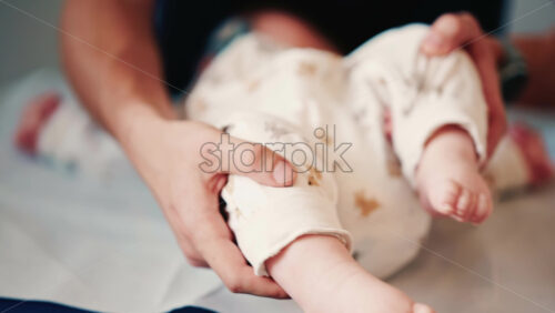 Video - Close up of an infant's legs and feet while caregivers gently reposition the baby during a care or examination session