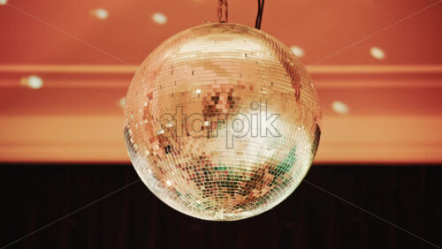 Video - Shiny disco ball reflecting light patterns in a warmly lit interior environment