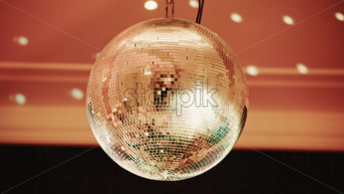 Video - Shiny disco ball reflecting light patterns in a warmly lit interior environment
