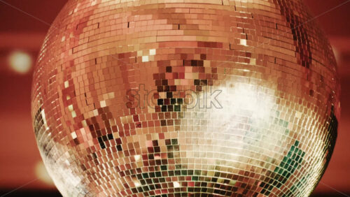 Video - Close up of a shiny disco ball reflecting light patterns in a warmly lit interior environment