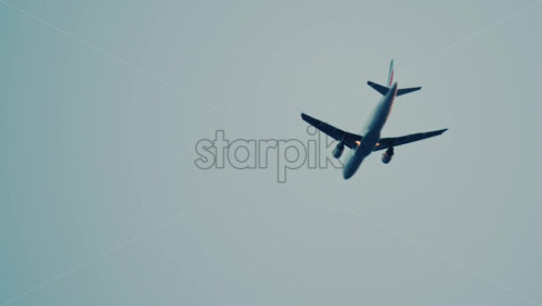 Video - Commercial airplane flying overhead against a clear blue sky, captured from below