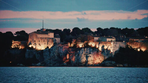 Video - Scenic view of a historic coastal fortress illuminated at dusk, overlooking the sea