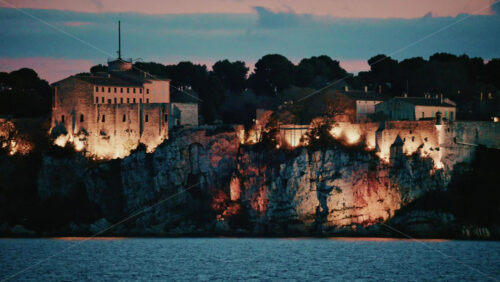 Video - Scenic view of a historic coastal fortress illuminated at dusk, overlooking the sea