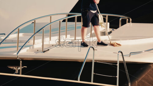 Video - Antibes, France - December 22, 2025: Man cleaning the deck of a luxury yacht moored at a marina on the French Riviera