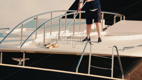 Video - Antibes, France - December 22, 2025: Man cleaning the deck of a luxury yacht moored at a marina on the French Riviera