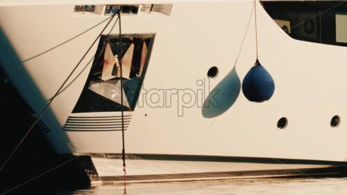 Video - Close up detail of a white yacht hull with hanging fenders and mooring ropes in a marina on the French Riviera