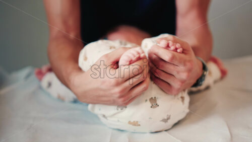 Video - Close up of an infant's legs and feet while caregivers gently reposition the baby during a care or examination session