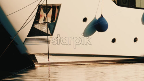 Video - Close up detail of a white yacht hull with hanging fenders and mooring ropes in a marina on the French Riviera