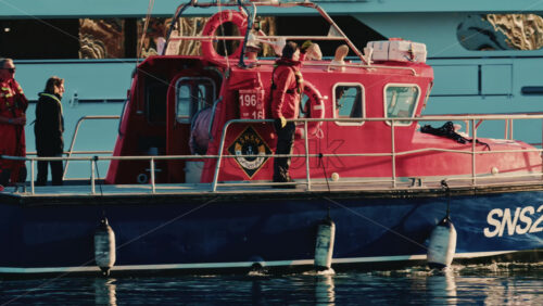Video - Antibes, France - December 22, 2025: Red French sea rescue boat docked in a marina with crew members on board