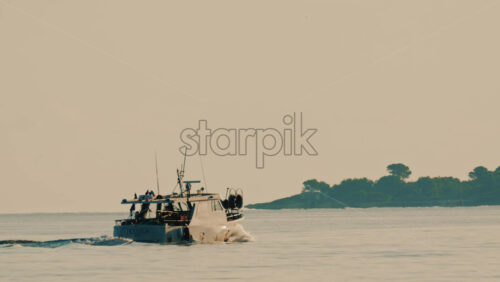 Video - Antibes, France - December 22, 2025: Small fishing boat navigating calm Mediterranean waters off the coast of France, with a luxury yacht visible in the background