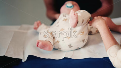 Video - Close up of an infant's legs and feet while caregivers gently reposition the baby during a care or examination session