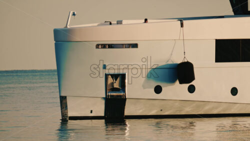 Video - Detailed close up of a luxury yacht hull with a hanging black fender and waterline visible