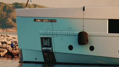 Video - Detailed close up of a luxury yacht hull with a hanging black fender and waterline visible