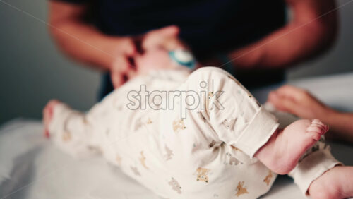 Video - Close up of an infant's legs and feet while caregivers gently reposition the baby during a care or examination session