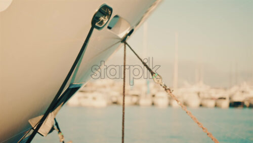 Video - Side view of a yacht bow secured with a rope and chain in a marina.