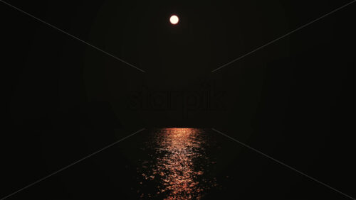 Video - Minimalist night scene showing the moon reflected on calm sea water