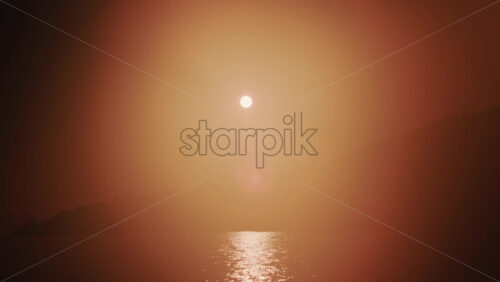 Video - Wide shot of the sunset illuminating the sea surface, creating a bright reflection on the water