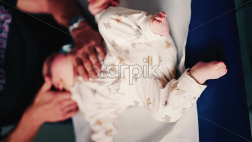 Video - Overhead view of a caregiver gently handling an infant during a medical or wellness session