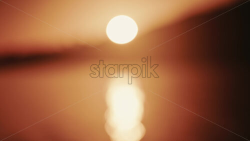 Video - Wide shot of the sunset illuminating the sea surface, creating a bright reflection on the water