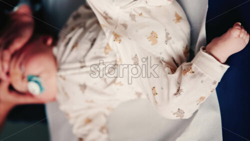 Video - Overhead view of a caregiver gently handling an infant during a medical or wellness session