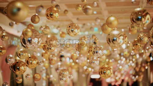Video - Decorative golden Christmas ornaments suspended in an elegant indoor display