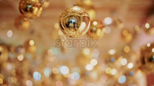 Video - Decorative golden Christmas ornaments suspended in an elegant indoor display