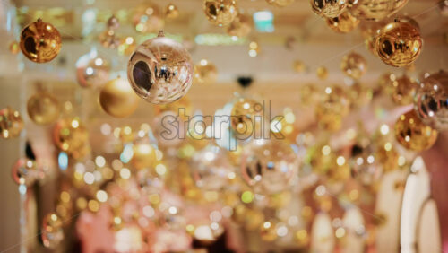 Video - Decorative golden Christmas ornaments suspended in an elegant indoor display
