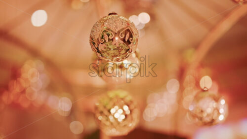 Video - Close up of a glittering Christmas bauble suspended indoors, illuminated by soft, warm lights