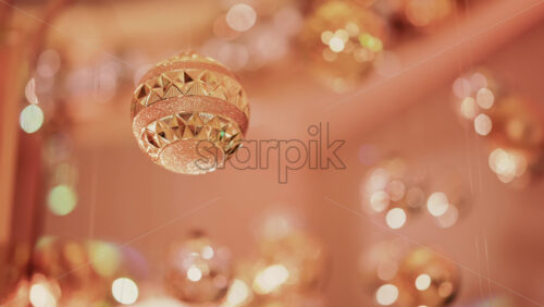 Video - Multiple golden Christmas ornaments hanging beneath a decorative indoor installation