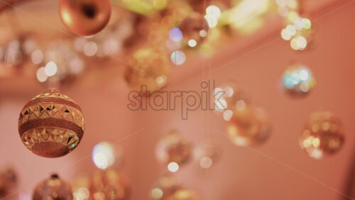 Video - Multiple golden Christmas ornaments hanging beneath a decorative indoor installation