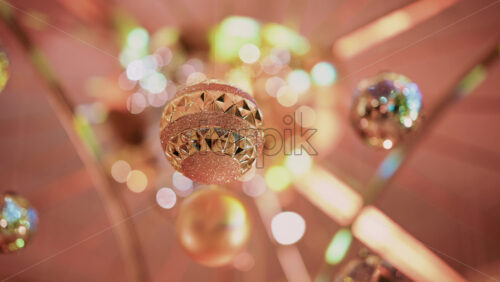 Video - Multiple golden Christmas ornaments hanging beneath a decorative indoor installation