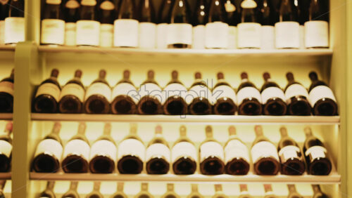 Video - Rows of wine bottles neatly arranged on softly lit shelves in a wine cellar or restaurant interior