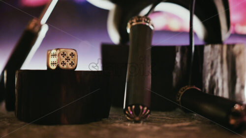 Video - Close up of decorative dice and gaming elements on a dark surface with neon-style lighting