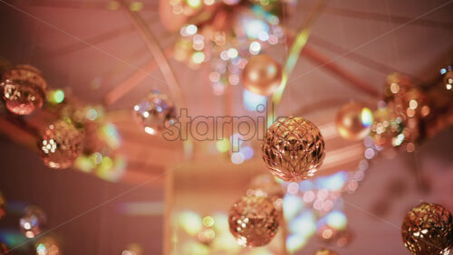 Video - Multiple golden Christmas ornaments hanging beneath a decorative indoor installation