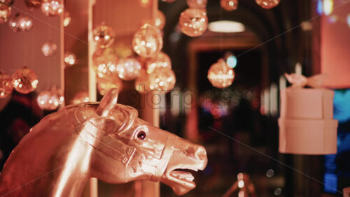 Video - Close up of a metallic horse decorative figure illuminated by warm Christmas lights, with ornaments visible behind it