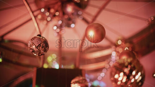 Video - Decorative Christmas baubles suspended from an ornate structure, glowing under warm indoor lighting