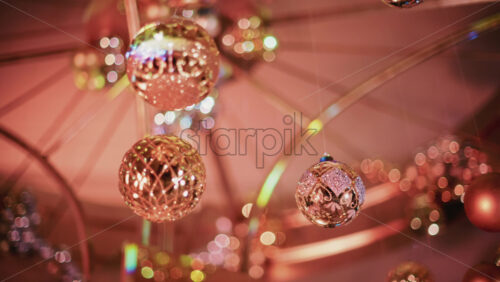 Video - Decorative Christmas baubles suspended from an ornate structure, glowing under warm indoor lighting