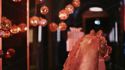 Video - Close up of a metallic horse decorative figure illuminated by warm Christmas lights, with ornaments visible behind it