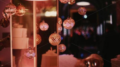 Video - Decorative Christmas baubles suspended from an ornate structure, glowing under warm indoor lighting