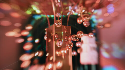 Video - Abstract shot of warm toned Christmas lights and hanging ornaments, blurred creating a festive bokeh effect