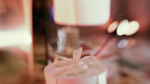 Video - Golden Christmas baubles hanging from a structure alongside a suspended white gift box, with people blurred in the background