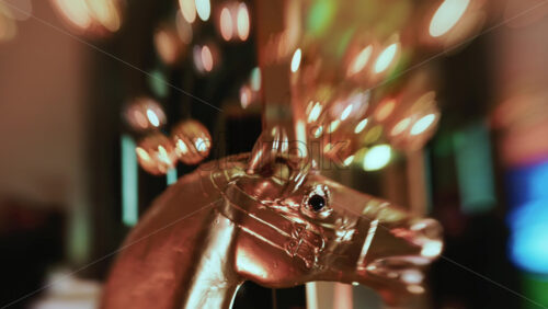 Video - Close up of a metallic horse decorative figure illuminated by warm Christmas lights, with ornaments visible behind it