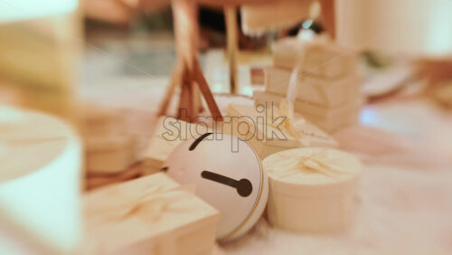 Video - Golden Christmas baubles hanging from a structure alongside a suspended white gift box, with people blurred in the background