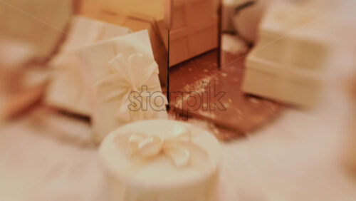 Video - Golden Christmas baubles hanging from a structure alongside a suspended white gift box, with people blurred in the background
