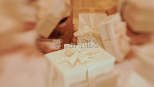 Video - Golden Christmas baubles hanging from a structure alongside a suspended white gift box, with people blurred in the background