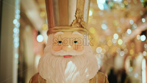 Video - Close up of a Santa Claus figure inside a festive Christmas installation with warm lights and ornaments