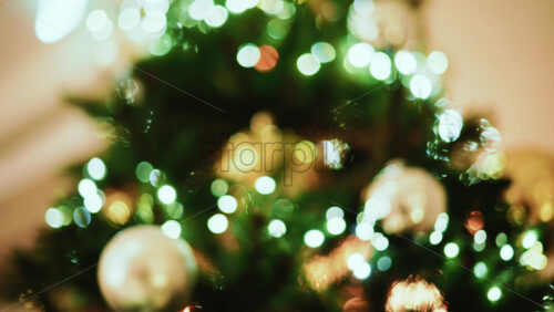 Video - Out of focus Christmas tree decorated with lights and ornaments in a festive indoor setting
